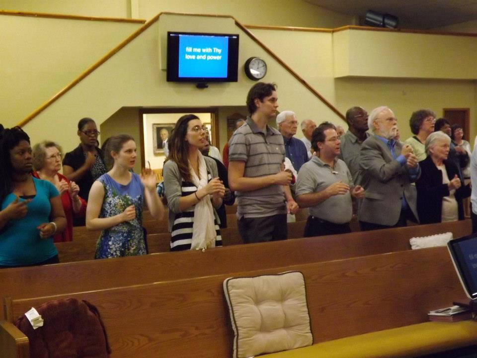 Younger and older congregation members standing together in worship